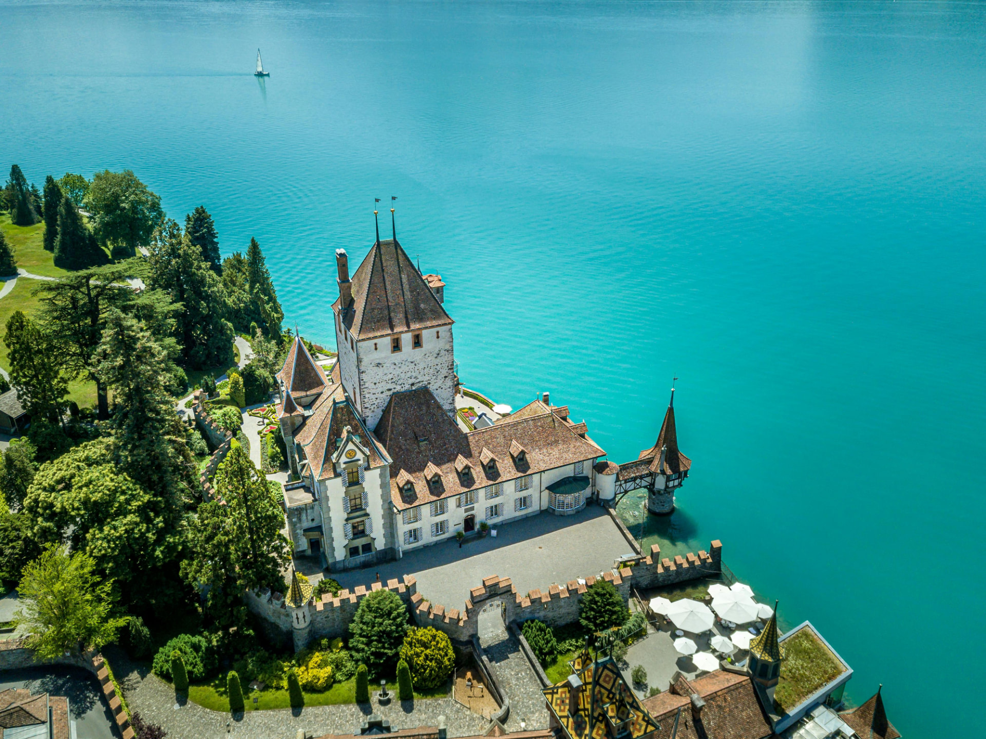 Swiss Alps luxury travel: a lakeside castle beneath snow-capped peaks in Switzerland, with cable cars and panoramic rail routes nearby