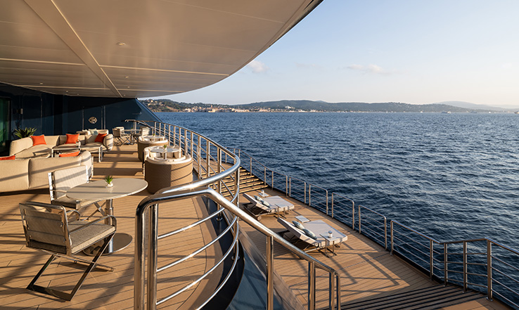 The teak Marina Terrace on a Ritz-Carlton Yacht Collection yacht, with lounge seating above the sea