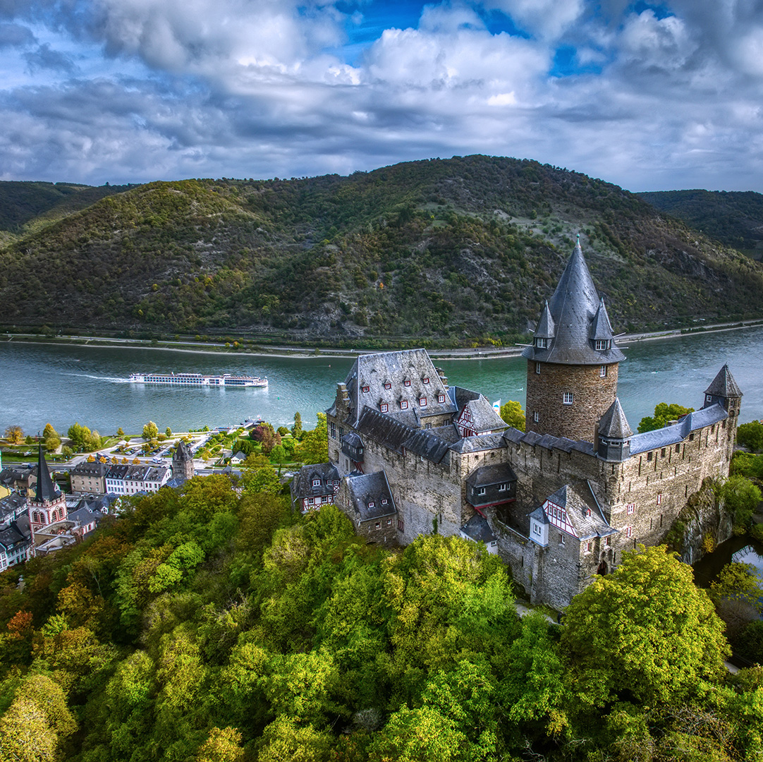 Rhine river cruise: Stahleck Castle above Bacharach, a European river cruise ship passing below in the UNESCO Upper Middle Rhine Valley
