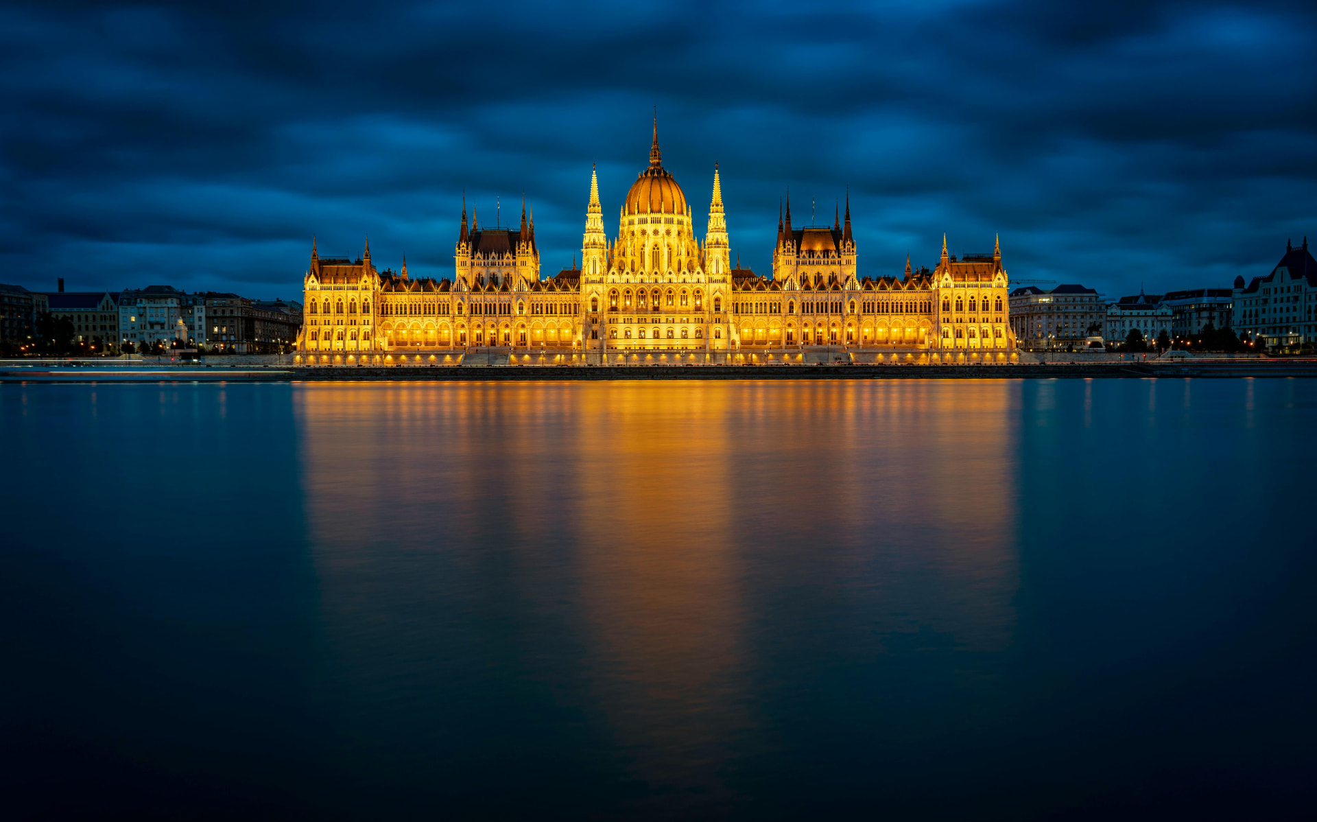 Danube river cruise: the Hungarian Parliament Building lit gold at night, reflected in the Danube in Budapest
