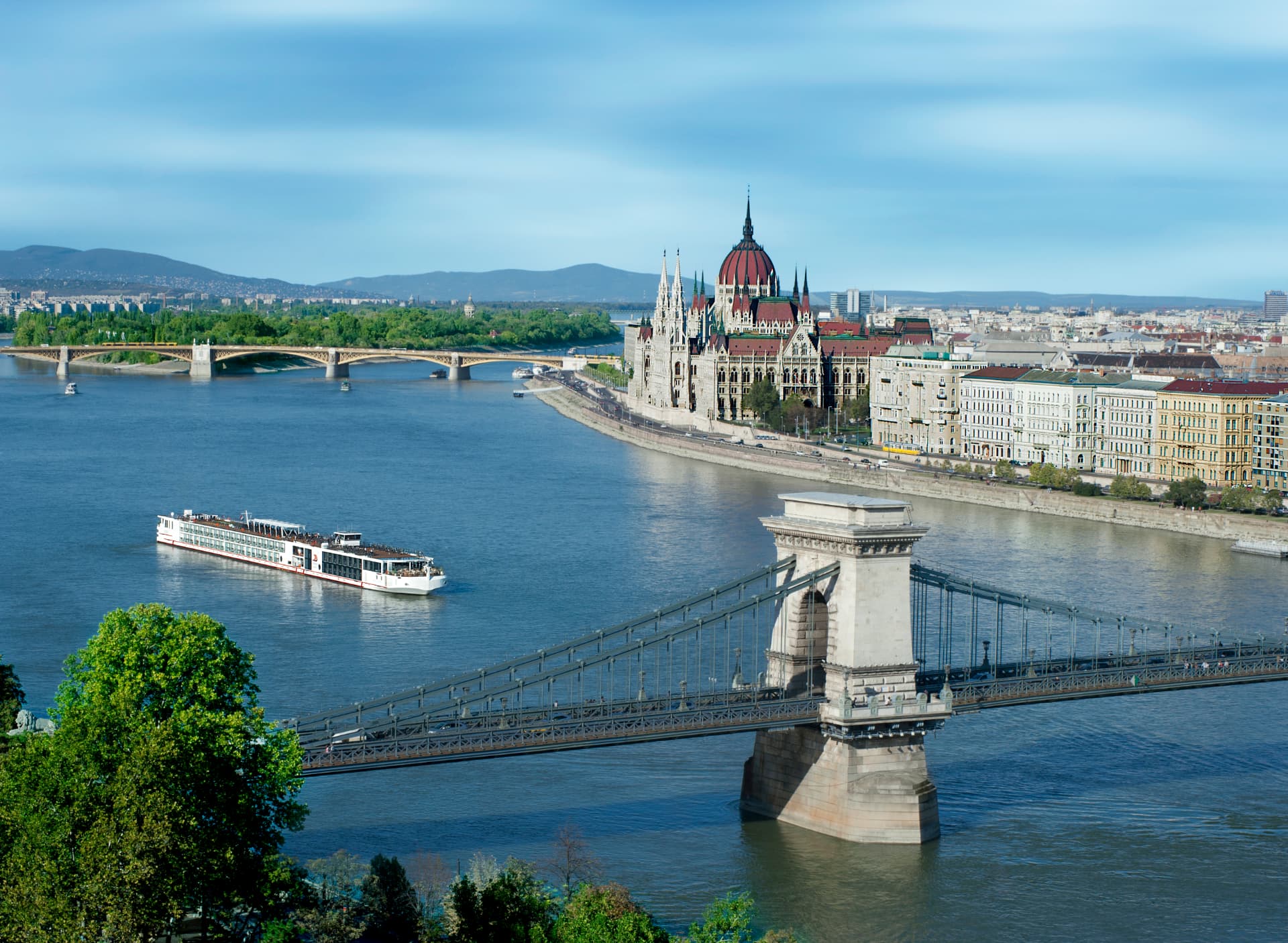 A river cruise ship sailing past the Chain Bridge and the Hungarian Parliament on the Danube in Budapest