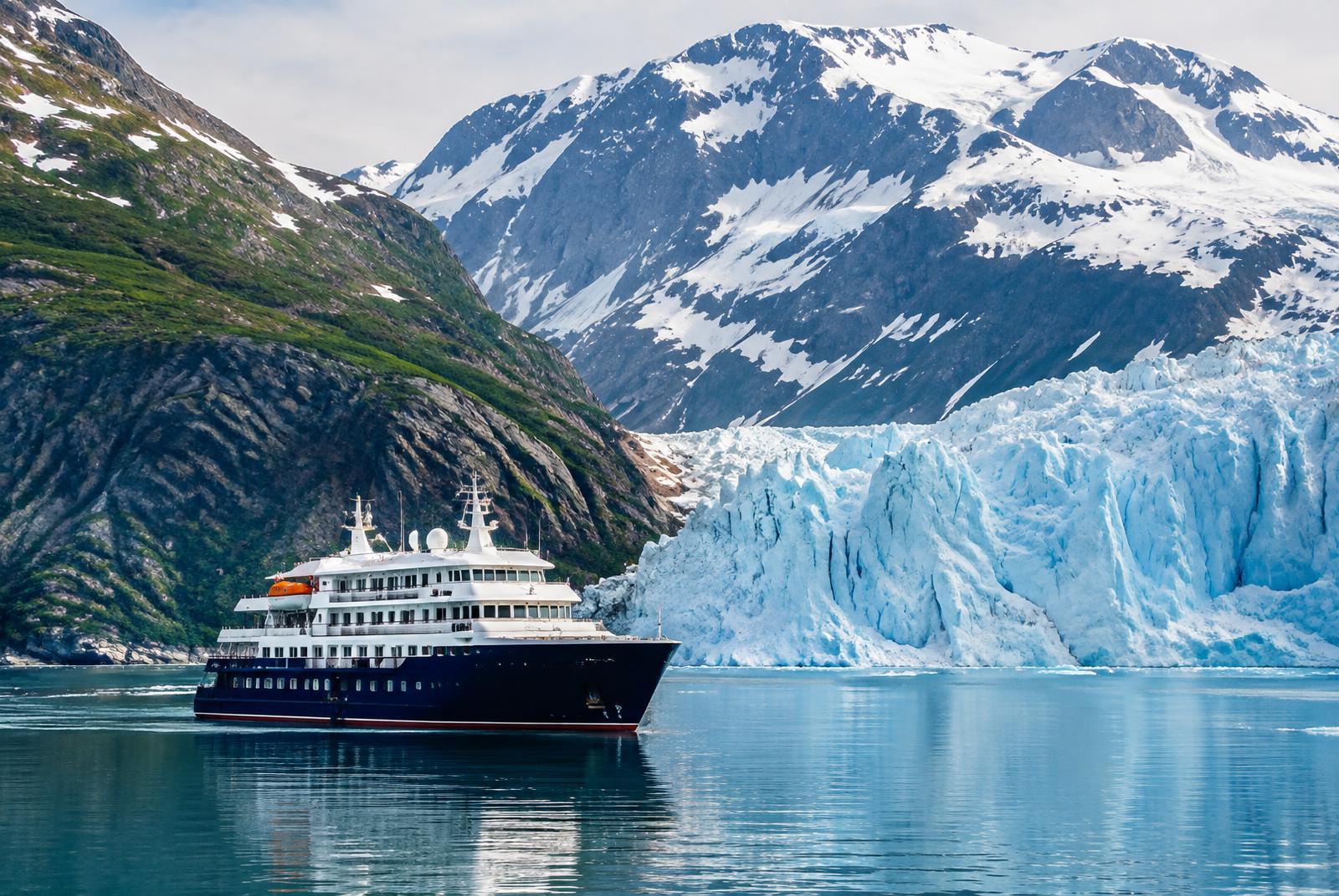 Alaska small-ship cruise: a luxury ship in an Inside Passage fjord beside a blue tidewater glacier and snow-capped mountains